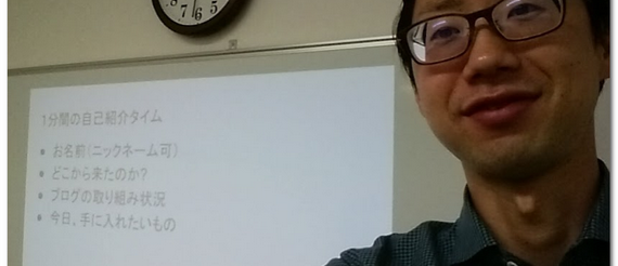 石黒の顔と後ろにホワイトボードと時計がある画像